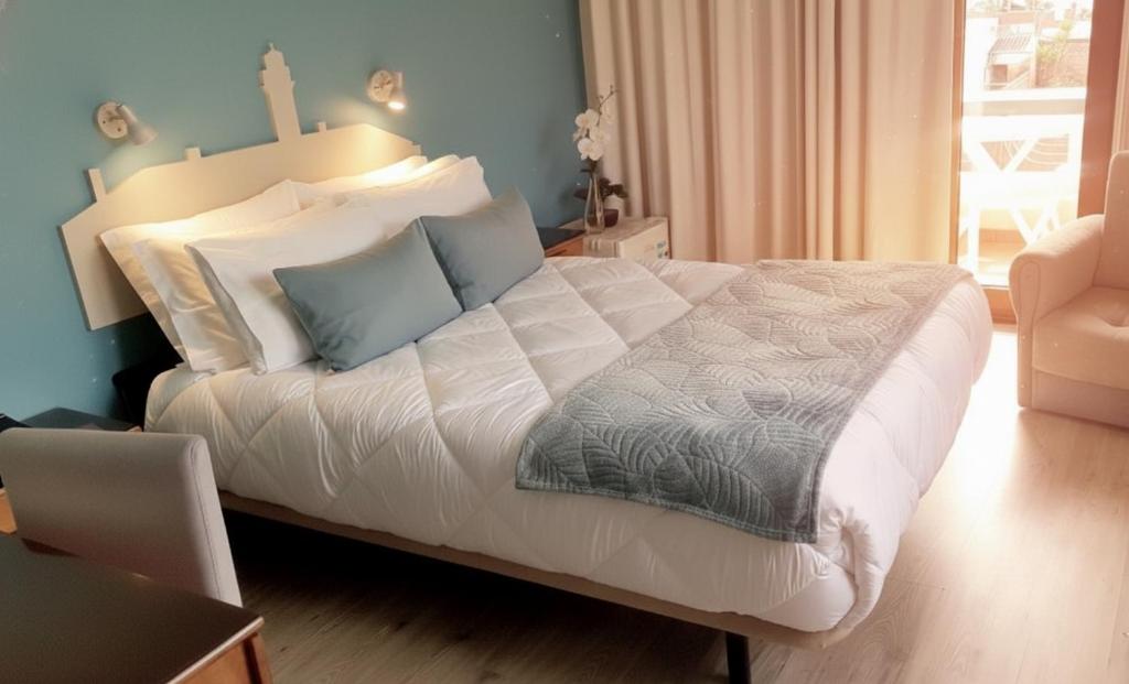 a bedroom with a bed with white sheets and blue pillows at Hotel Areias Claras in Viana do Castelo