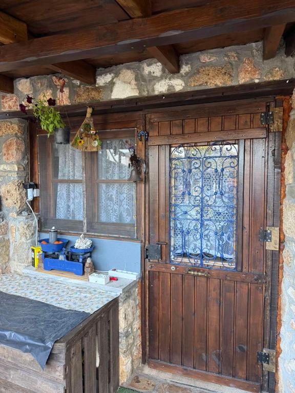 a wooden door with a window in a stone building at Lithos Home in Panagia