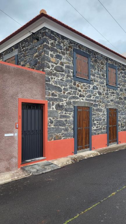 a brick building with two doors on a street at Refúgio do Santa in Calheta