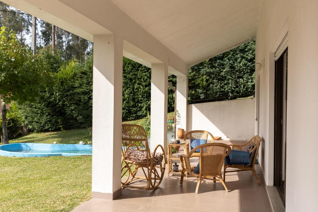 a porch with chairs and a table and a pool at Ermal Green Haven in Vieira do Minho
