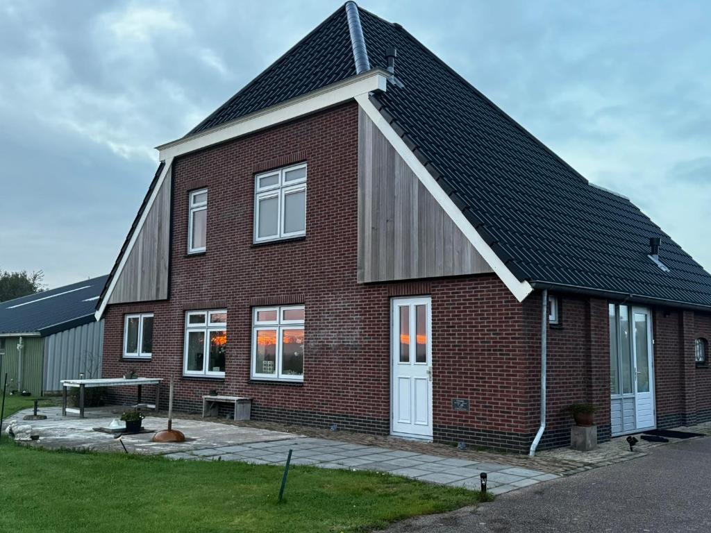 a red brick house with a gambrel roof at Bed en Bike Oudeschild in Oudeschild