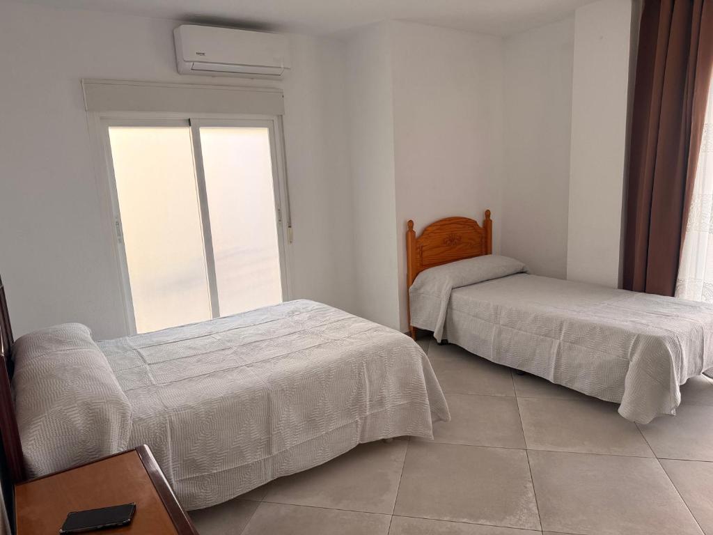 a bedroom with two beds and a large window at Habitación Doble con Aire cerca de la Playa in Benidorm