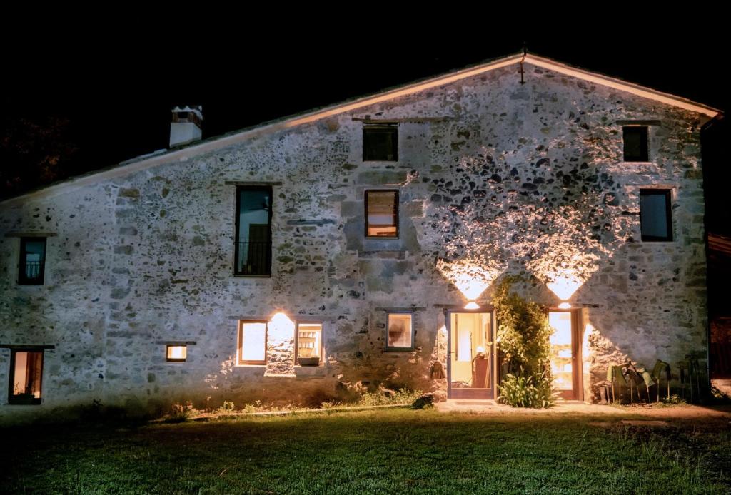 an old stone house with lights on it at night at Mas Casalprim in Sant Feliu de Pallerols