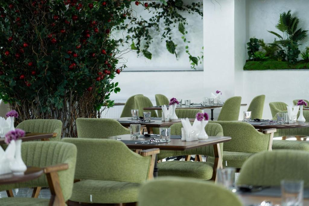 a dining room with tables and green chairs at Rauza Hotel Tashkent in Tashkent