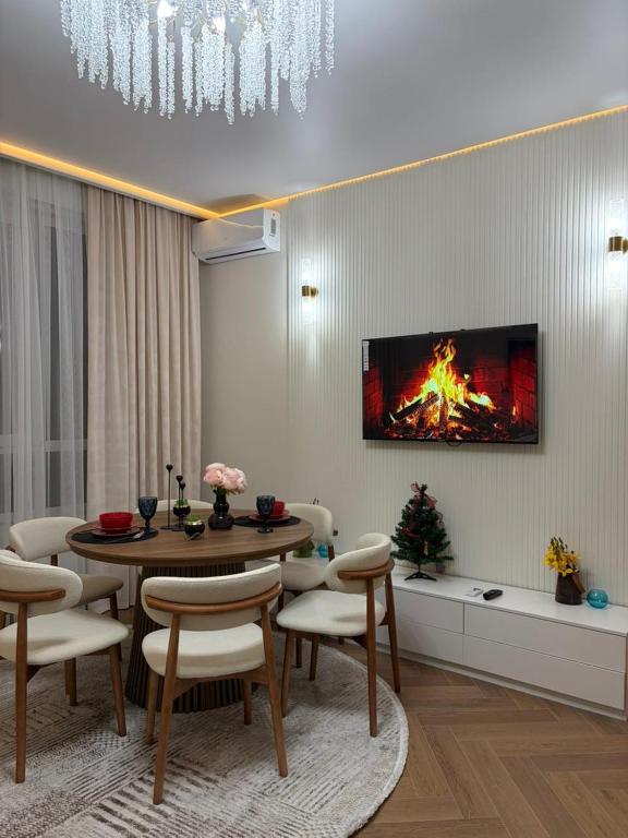 a living room with a table and a fire on the wall at Prime Stay Almaty & VIP Apartment in the center in Almaty