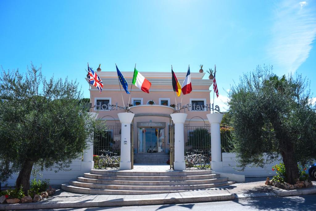 un edificio con banderas en la parte delantera en Hotel d'Altavilla, en Canosa di Puglia