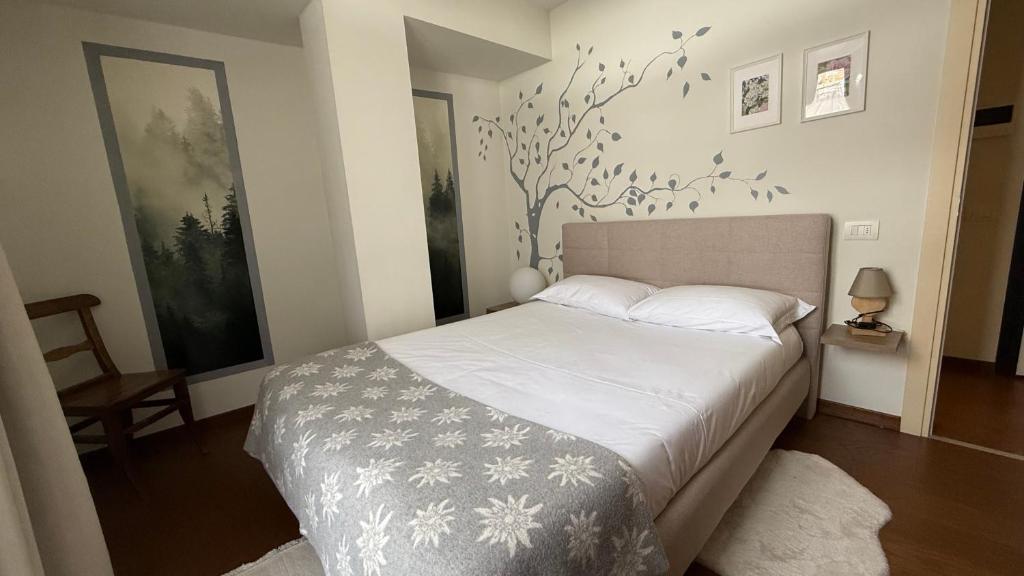 a bedroom with a bed and a tree mural on the wall at Maison Poluc - Maison Adeline in Champoluc