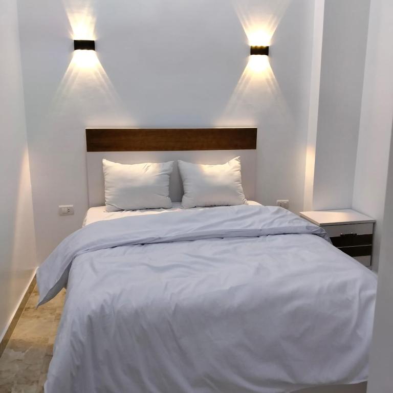 a bedroom with a white bed with two lights on it at Diamond in Luxor