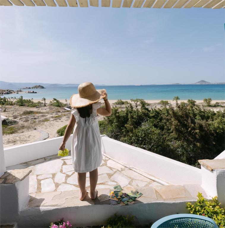 a woman in a hat looking out at the beach at Victoria Studios & Apartments in Mikri Vigla