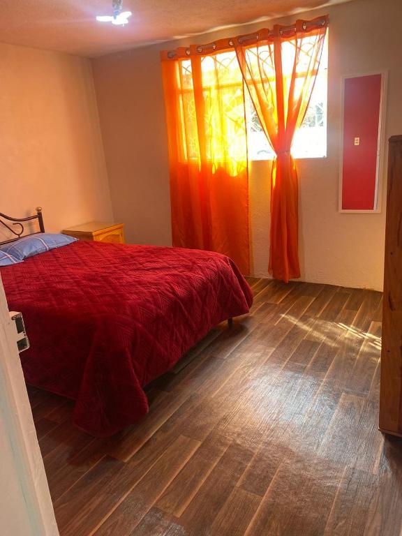 a bedroom with a red bed and a window at Casa Ecológica Angangueo in Mineral de Angangueo
