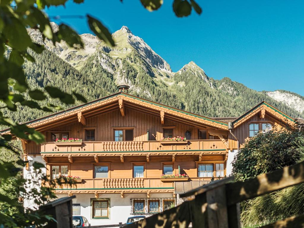 a large wooden building with a mountain in the background at Brückenhof in Finkenberg