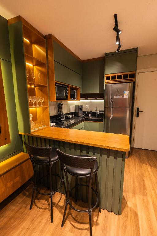 a kitchen with green cabinets and a bar with stools at Studio Prime Cuiaba 1709 in Cuiabá