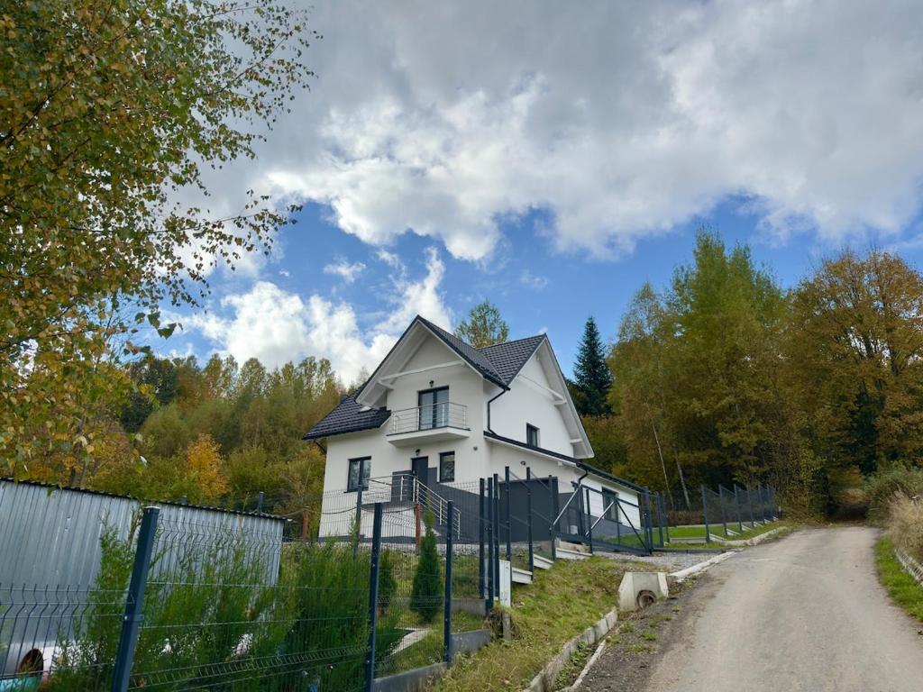 a white house on the side of a road at Między Wzgórzami Korbielów in Korbielów