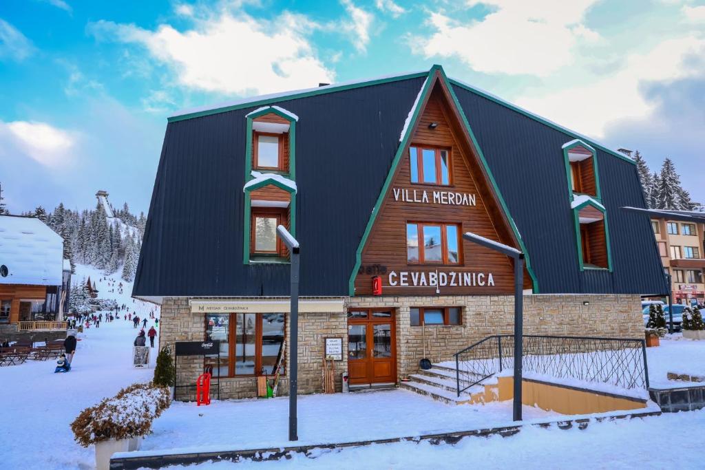 a building with a black roof in the snow at Villa Merdan in Vlasic