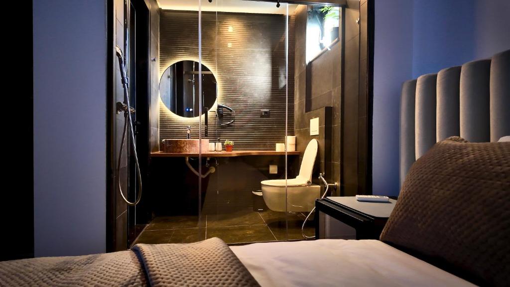 a bathroom with a sink and a toilet and a mirror at Fivenco Suites - Private Suites w King Bed Modern in Tirana