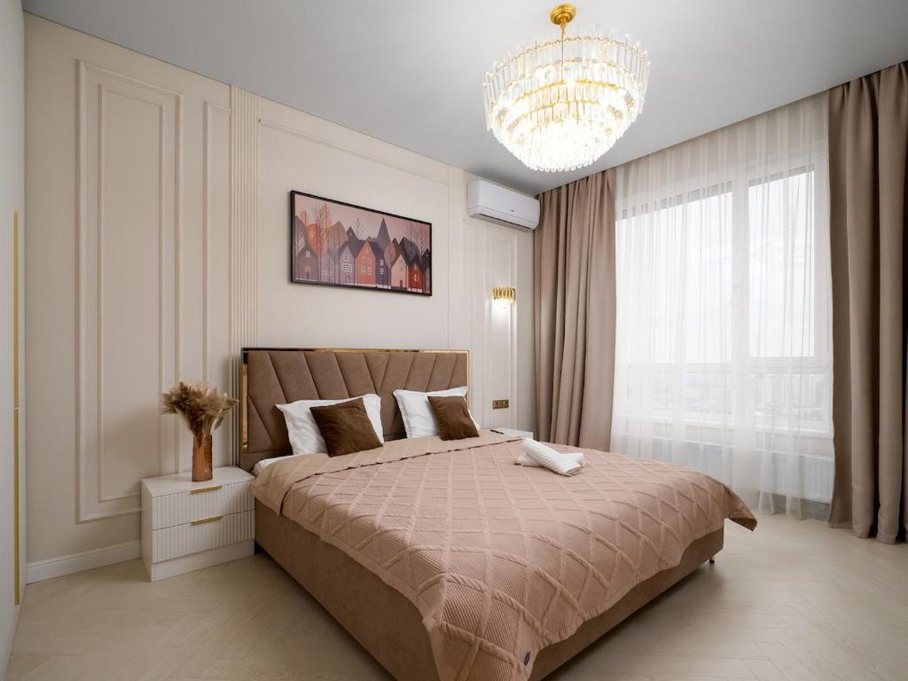 a bedroom with a large bed and a chandelier at Smart Lux 200 in Zhezdi