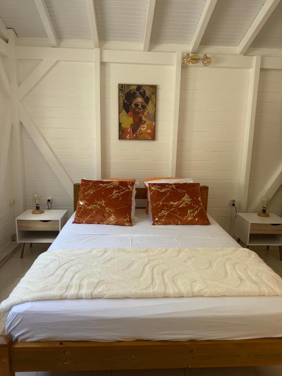 a bedroom with a large white bed with two pillows at Golden Vibes in Petit-Bourg
