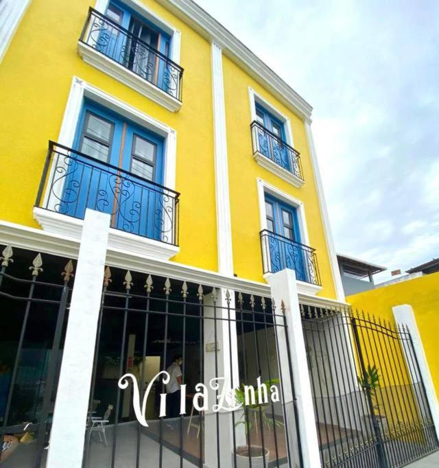 a yellow building with blue doors and balconies on it at Pousada VilaZinha in Vila Velha
