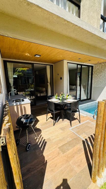 a patio with a table and chairs and a pool at Sunset Villas Milagres - Casa Anahi in Passo de Camarajibe