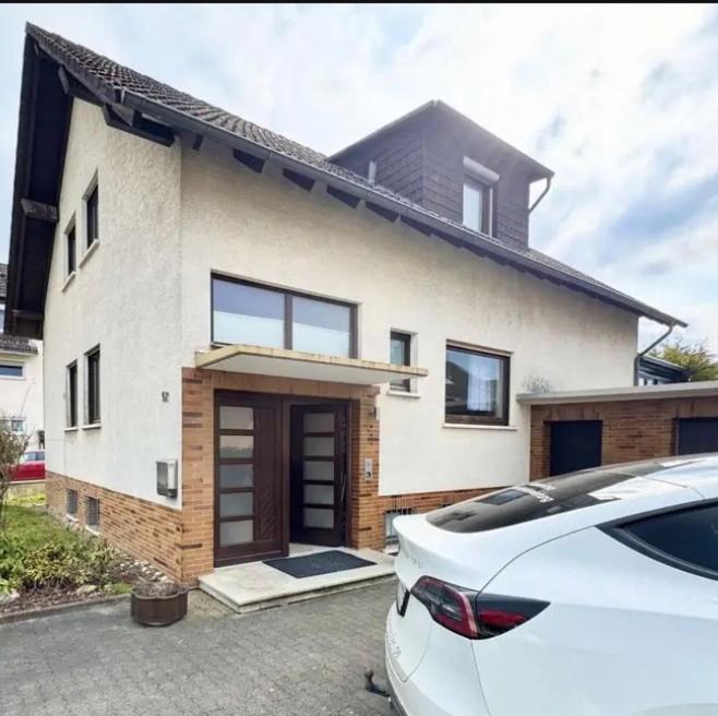 a white house with a car parked in front of it at YOLKI HAUS moderne Apartments, nahe Wölfersheimer See in Wölfersheim