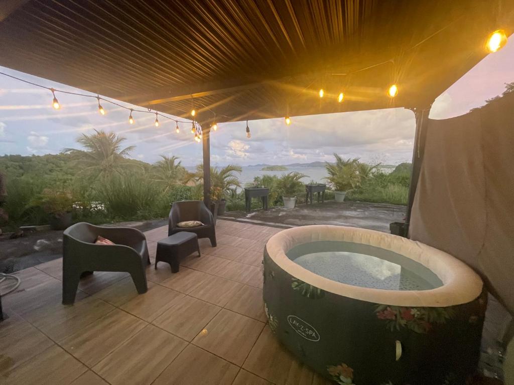 a hot tub in a tent with chairs and a patio at Estrella, véritable havre de paix climatisé avec spa in Sainte-Marie