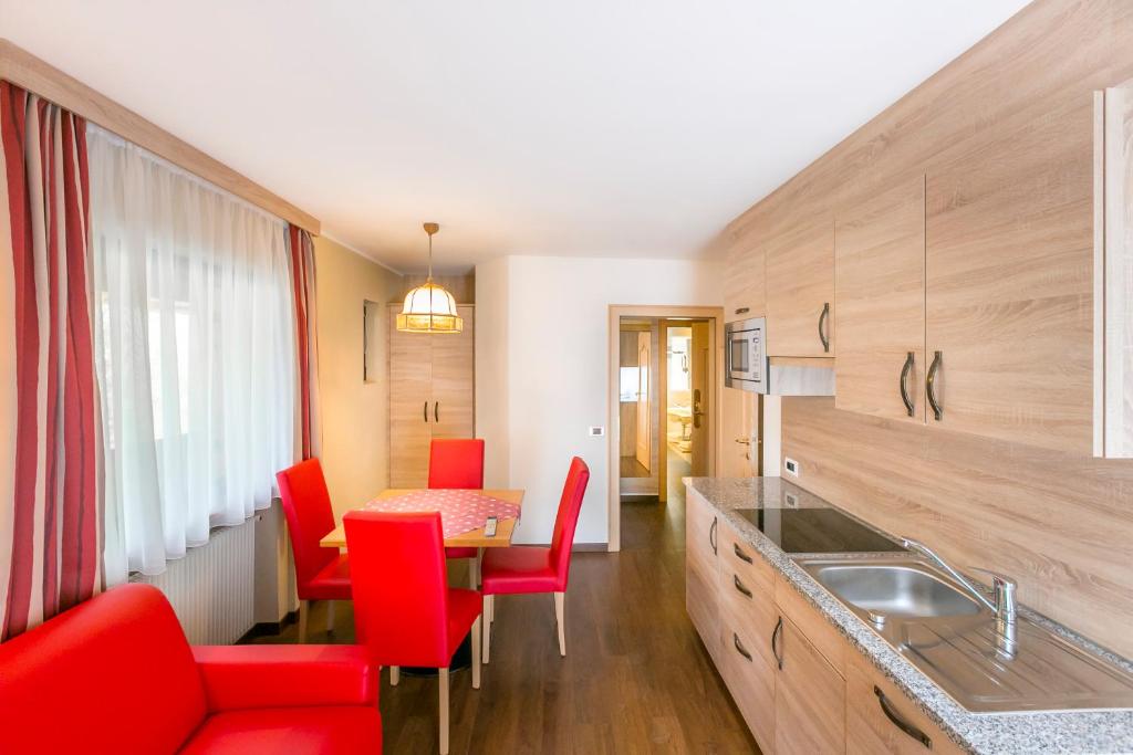 kuchnia z czerwonymi krzesłami i stołem w obiekcie Apartments Diamant w mieście Ortisei