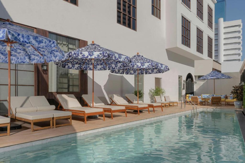 a pool with chairs and umbrellas next to a building at Metropole, Bangkok, a Tribute Portfolio Hotel in Bangkok