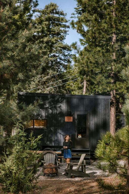 a woman standing in front of a black tiny house at Postcard Cabins Western Catskills, Outdoor Collection by Marriott Bonvoy in Roscoe