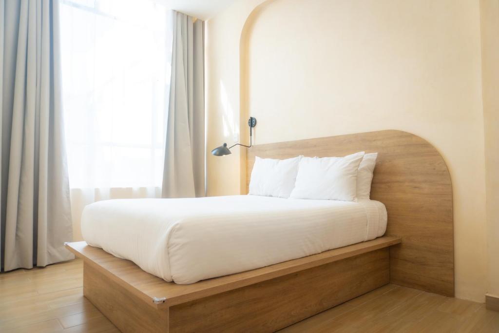a bed with a wooden headboard in a room at Hotel & hostal Morada in Puebla
