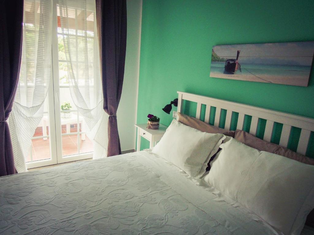 a bedroom with a bed with a green wall and a window at B&B La Rosa dei Venti in Ginosa Marina