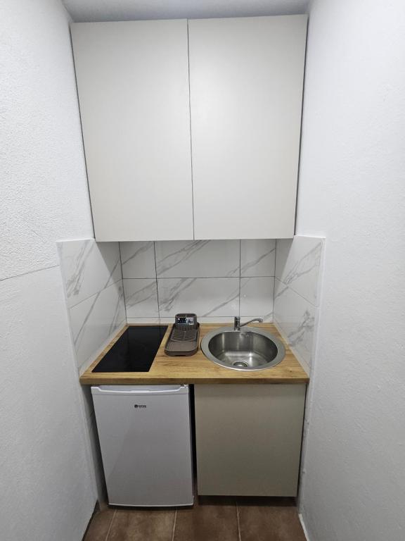 a small kitchen with a sink and white cabinets at Montana apartman in Han Pijesak