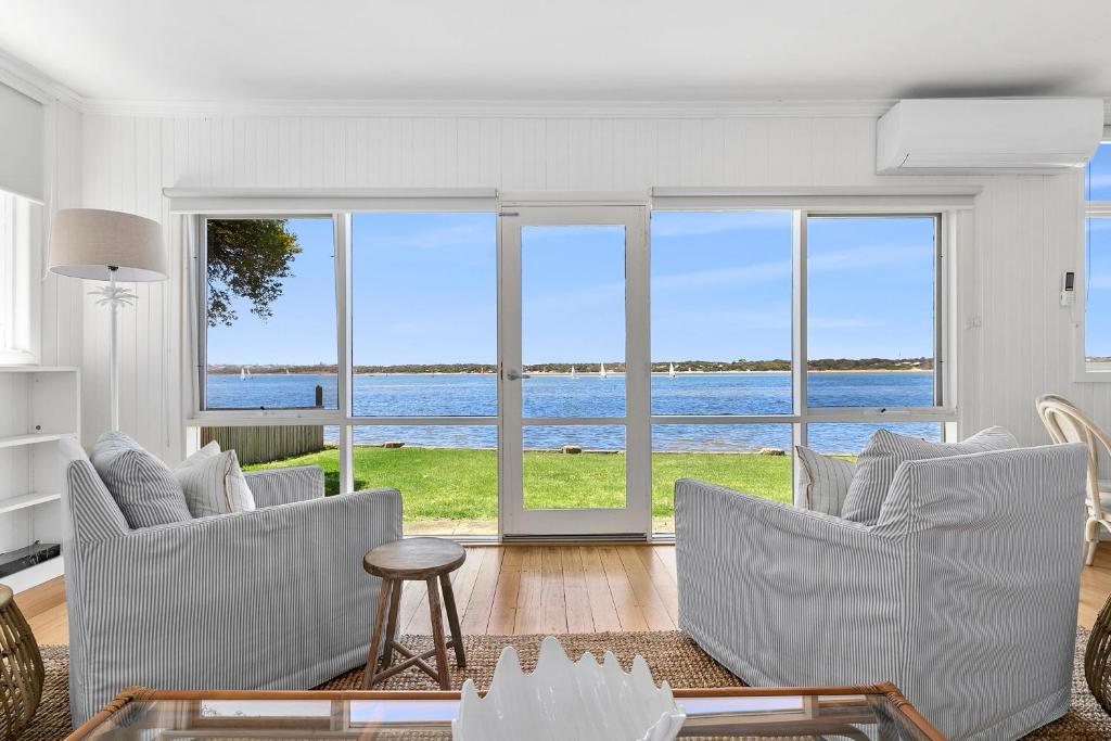 a living room with chairs and a view of the water at River Meets Ocean Edge - Absolute Waterfront in Barwon Heads