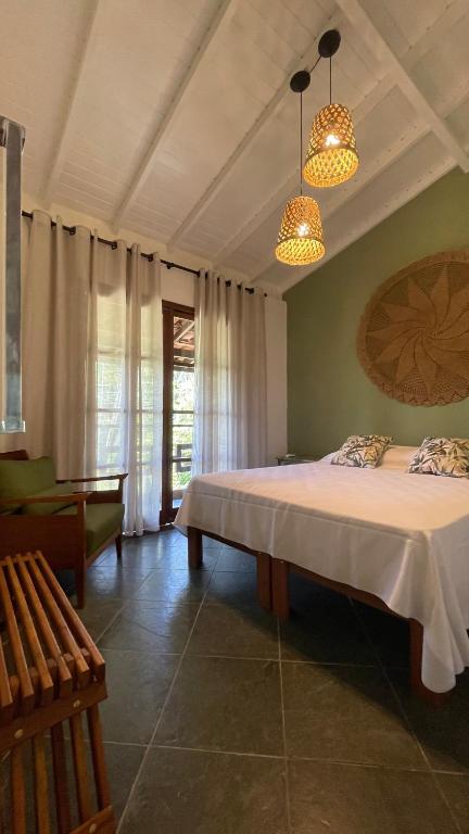 a bedroom with a large bed and two lights at Casa Aroeira Sahy in Barra do Sahy