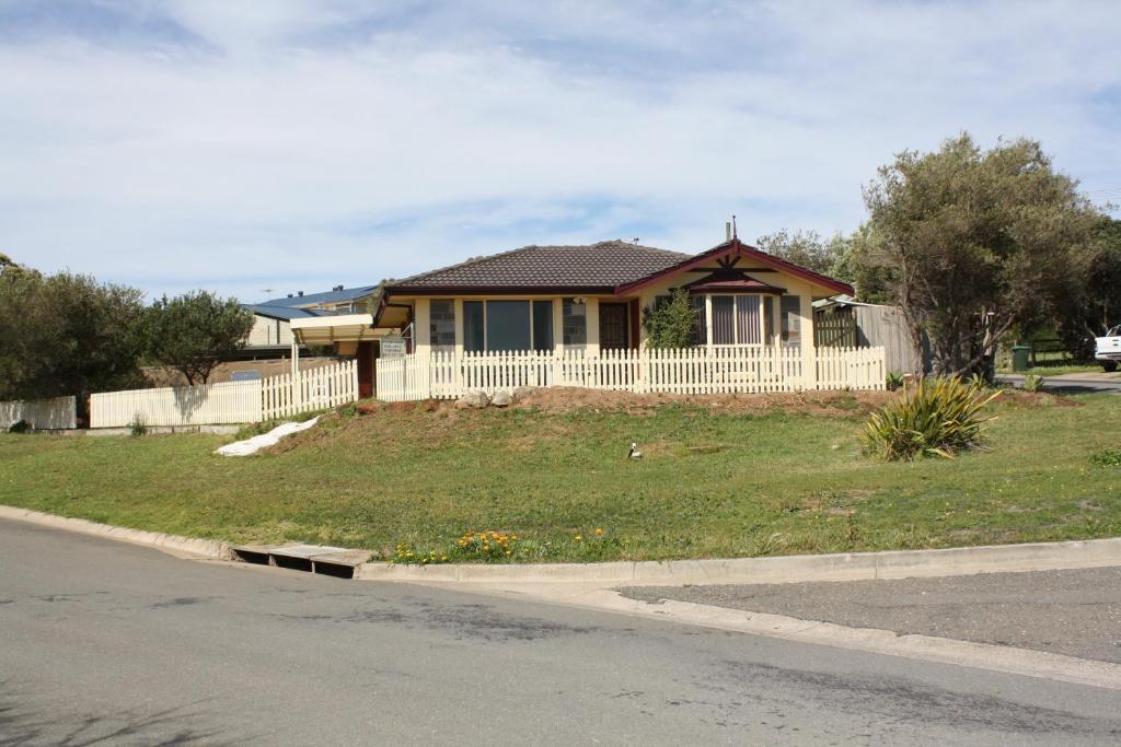 a house with a white fence in front of a yard at Maslin Beach House in Maslin Beach