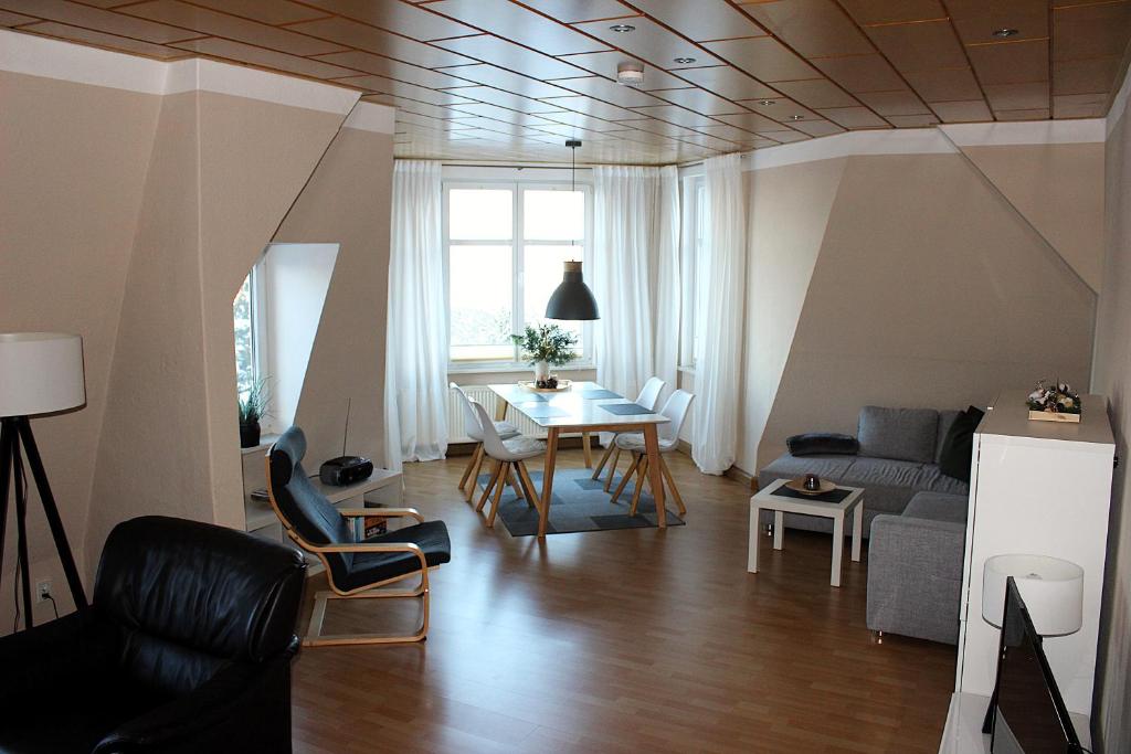 a living room with a couch and a table and chairs at Villa Schlossblick I - Zeit zum Entspannen in exklusiver Ferienwohnung mit Panoramablick, Parkplatz, WLAN, Smart-TV in Wernigerode