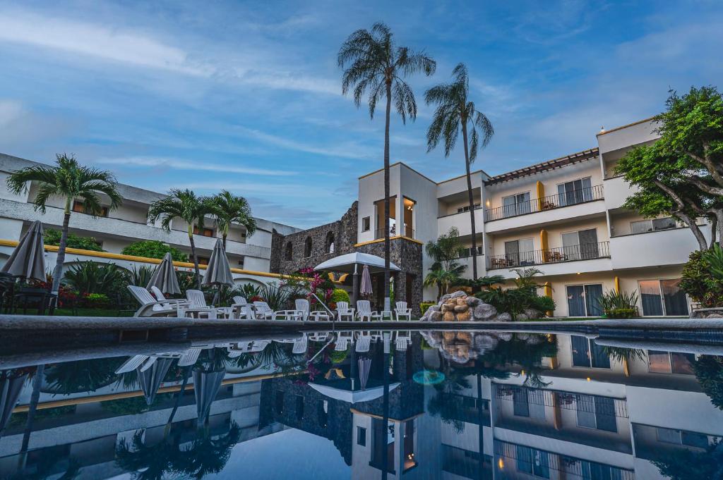 a hotel pool with chairs and palm trees at Casa Francisco in Cuernavaca