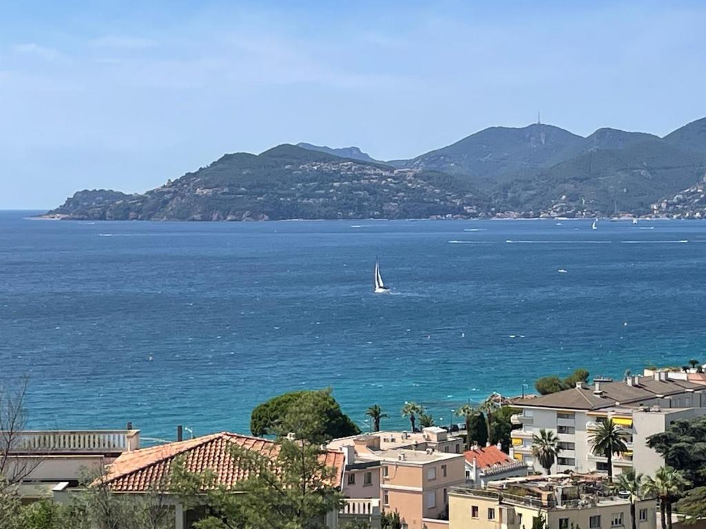 a sail boat in the water with houses and mountains at Splendid view Apartment in Cannes in Cannes