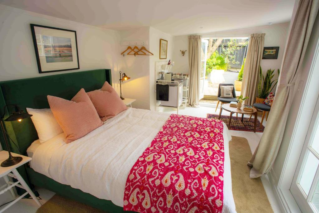 a bedroom with a large bed with a red and white blanket at Finnis Studio in Napier