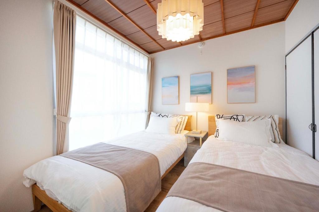 two beds in a room with a window at KURIHAMA Base 102 in Kubiri