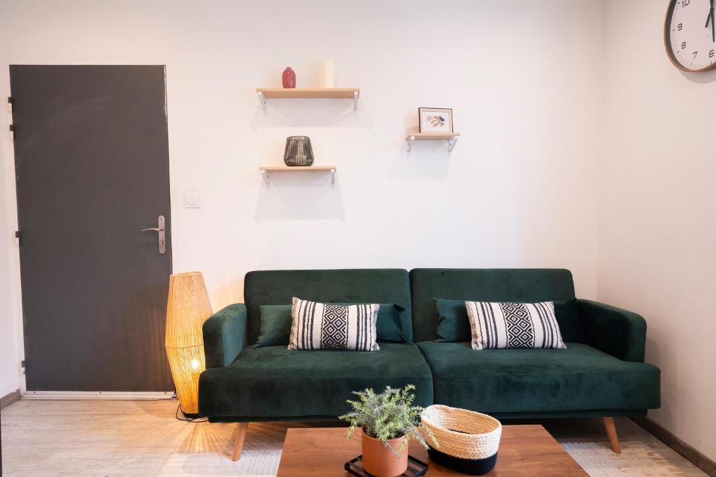 a green couch in a living room with a clock at Instant Pyrénéen in Lourdes
