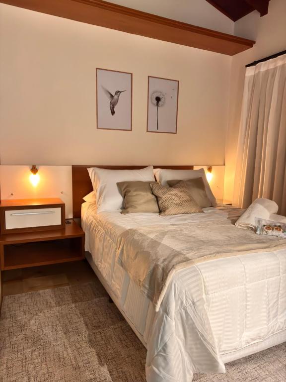 a bedroom with a large white bed with a night stand at Pousada Vivenza - Suíte 03 e 04 in Laguna