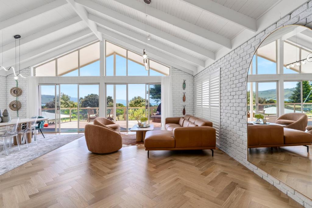 a living room with leather furniture and large windows at Apollo Bay Gone Surfin in Apollo Bay