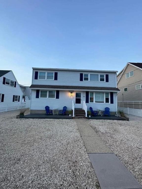 a white house with blue chairs in a driveway at Lbi - Ship Bottom, Duplex Available For Summer 2026 in Ship Bottom