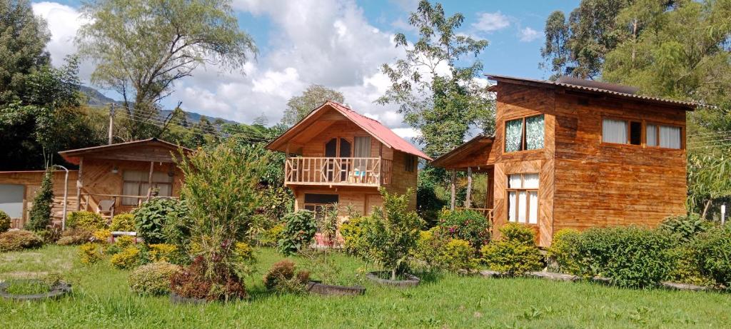 a log house in a field with a yard at Cabañas Sumak Kawsay in Colón