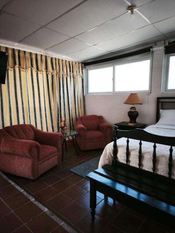 a bedroom with a bed and two chairs and a couch at Nirvana 2, Habitación doble con todos sus servicios in Guatemala