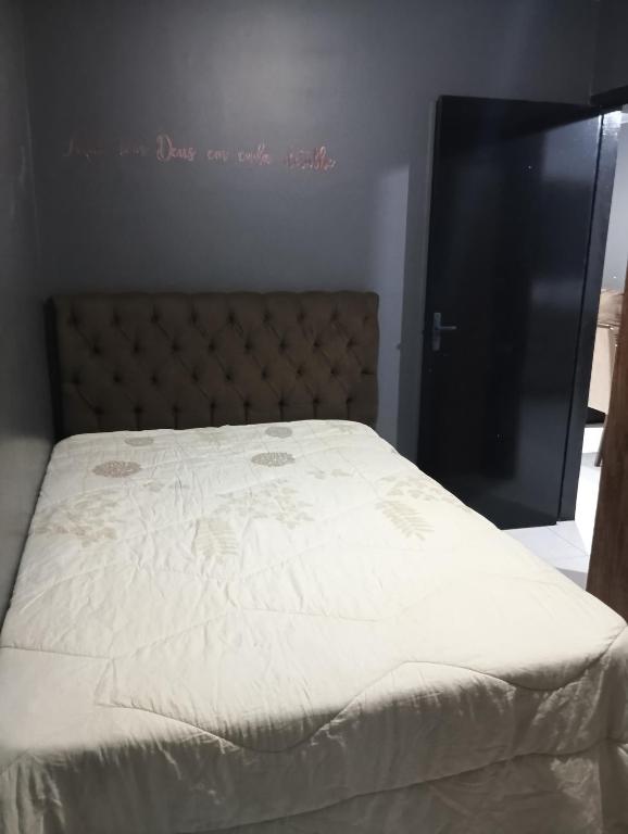 a bedroom with a bed with white sheets and a black door at Casa inteira in Ponta Grossa