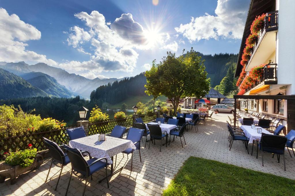 eine Terrasse mit Tischen und Stühlen mit Bergen im Hintergrund in der Unterkunft Bed&Breakfast Lausegger in Ferlach