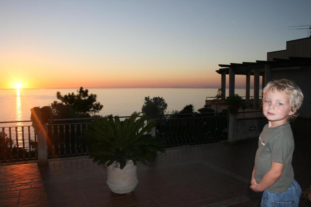 a young boy standing on a balcony with the sunset at Villa Bella Vista in Castellabate