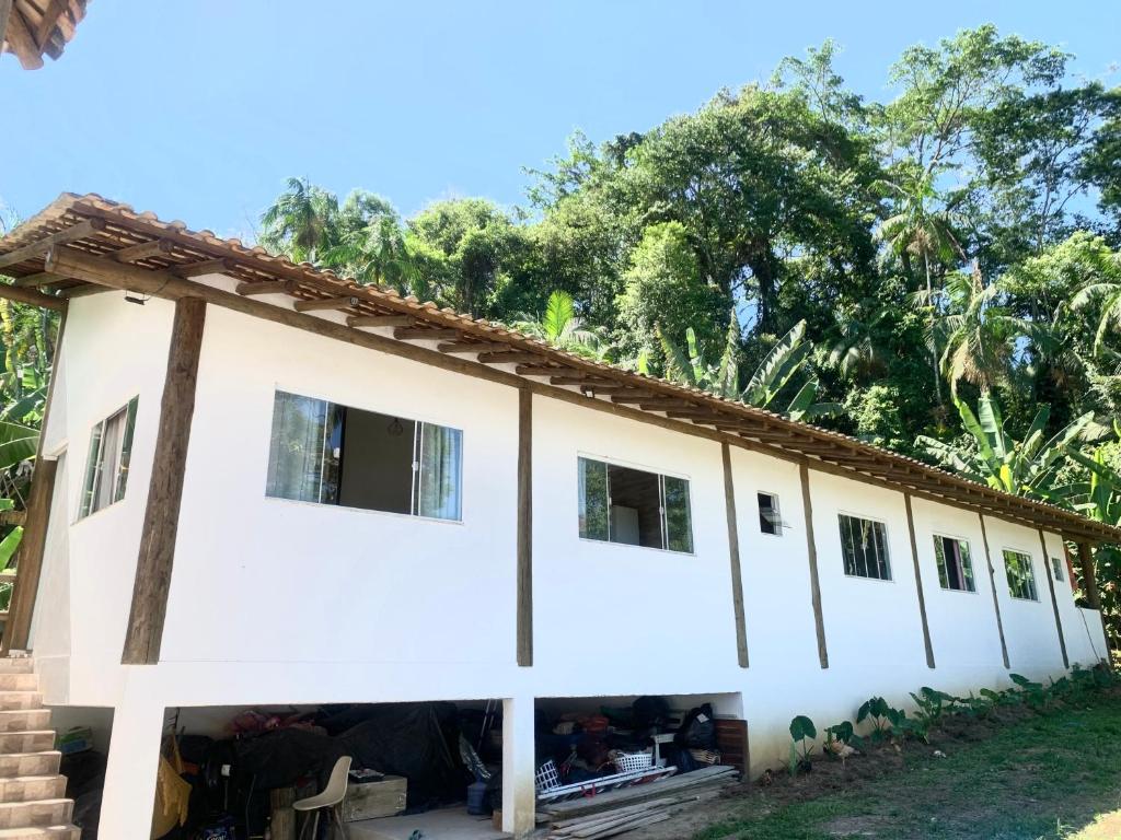 a large white building with trees in the background at Refúgio da Nicinha a 7 min do Centro Histórico in Paraty