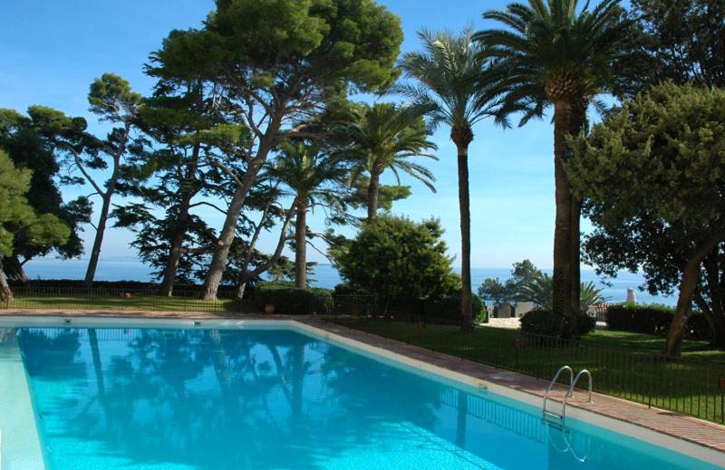 a blue swimming pool with palm trees in the background at Residence port la galere in Théoule-sur-Mer